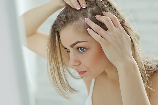 a woman examining her hair for hair loss prevention