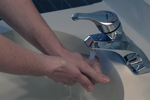 Person washing hands under running water in sink