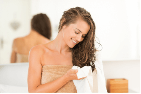 Woman wrapped in towel, drying her hair with a smaller towel